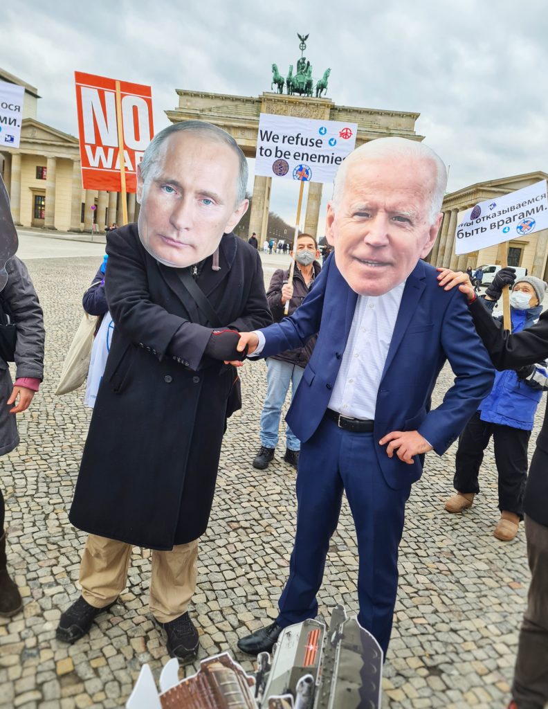 Als Vladimir Putin und Joe Biden verkleidete Aktivist*innen reichen sich vor dem Brandenburger Tor symbolisch die Hand im Ukraine-Konflikt