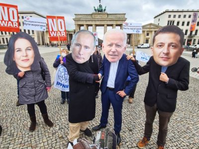 Als Baerbock, Putin, Biden und Selensky verkleidete Aktivist*innen reichen sich vor dem Brandenburger Tor symbolisch die Hand im Konflikt zwischen Ukraine, NATO und Russland