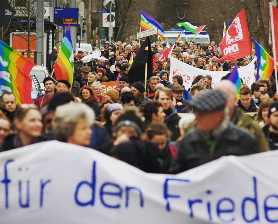 Foto einer Friedensdemo mit Fahnen und Bannern